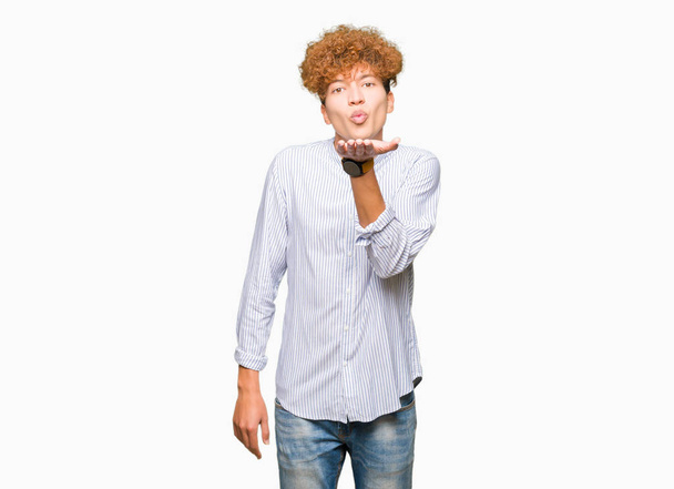 Mladý pohledný obchodní muž s afro vlasy nosí elegantní tričko při pohledu na fotoaparát Naznačení polibku s rukou na vzduchu jsou krásné a sexy. Láska výraz. - Fotografie, Obrázek
