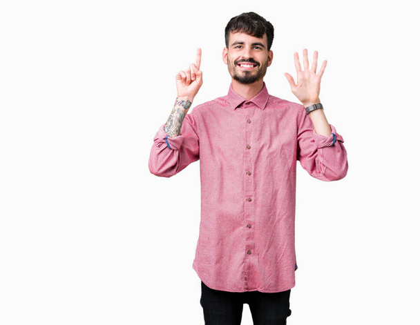 Rózsaszín inget visel, mint elszigetelt háttér bemutatás és ujjal felfelé mutató jóképű fiatalember száma hat, miközben mosolyogva, magabiztos és boldog. - Fotó, kép