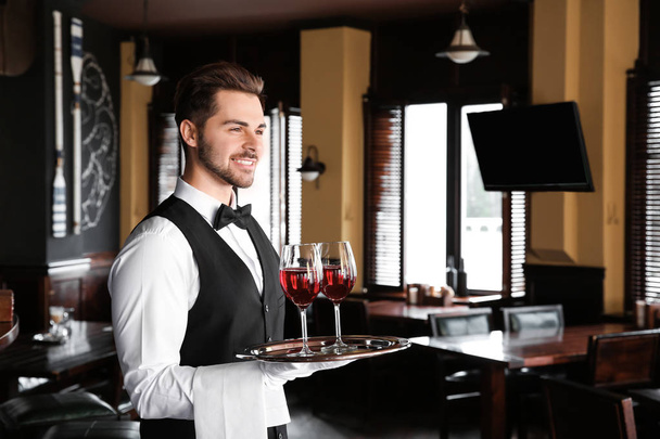Young male waiter with glasses of wine in restaurant - Photo, Image