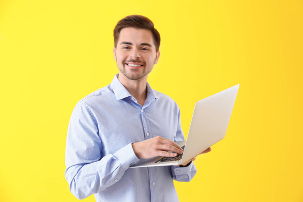 Male programmer with laptop on color background - Foto, afbeelding