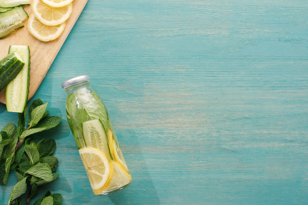 top view of detox drink in bottle with lemon and cucumber slices and mint  - Фото, изображение