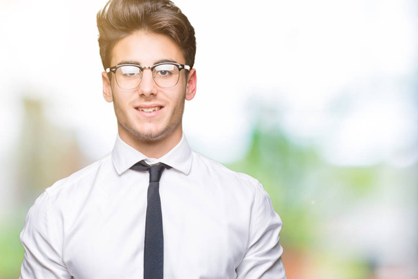 Young business man wearing glasses over isolated background with a happy and cool smile on face. Lucky person. - Zdjęcie, obraz