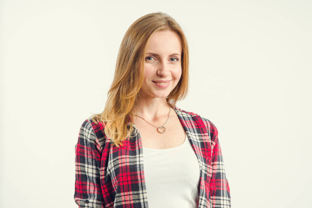 Portrait of a beautiful woman in a t-shirt and red plaid shirt standing on a light background. - Foto, Imagen