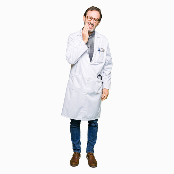 Středním věku lékař muži nosí lékařský kabát dojemné ústa rukou s bolestný výraz kvůli bolesti zubů nebo zubní nemoci na zuby. Zubař koncept. - Fotografie, Obrázek