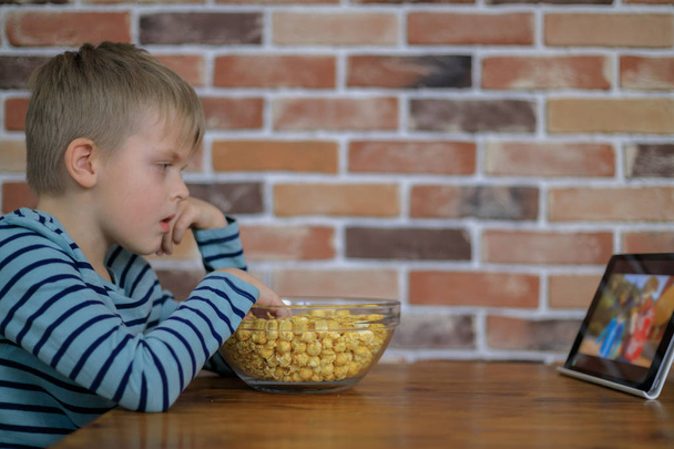 Junge schaut auf digitales Tablet mit Popcorn - Foto, Bild