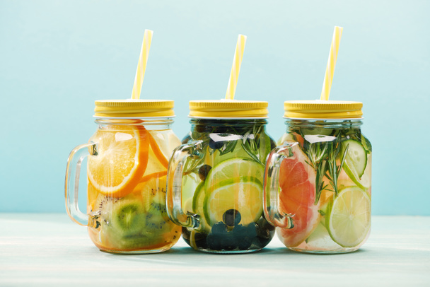 fresh organic detox drinks with berries, fruits and vegetables in jars with straws isolated on blue  - Photo, Image