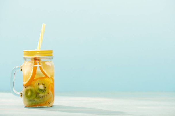 boisson de désintoxication dans un bocal aux oranges, kiwi et paille isolé sur bleu
 - Photo, image