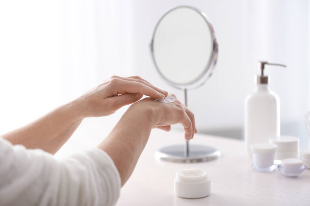 Mature woman applying hand cream at home - Fotografie, Obrázek