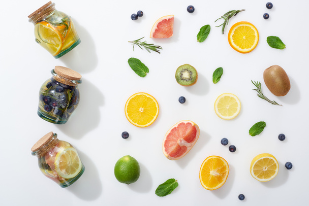top view of detox drinks in jars near fruit slices, blueberries and herbs - Foto, imagen