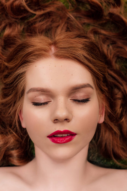 top view of beautiful young redhead woman with red lips and eyes closed - 写真・画像