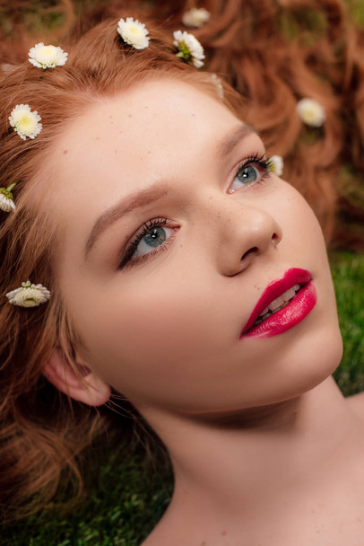 portrait of beautiful young redhead woman with red lips and chrysanthemum flowers in hair - Foto, immagini