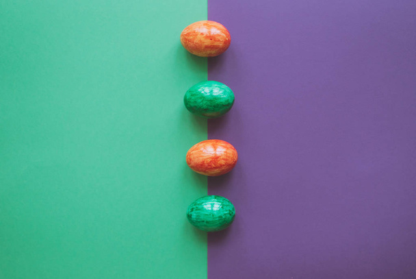 Easter eggs on green and violet background. - Φωτογραφία, εικόνα