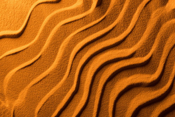 felülnézet a homokos háttérrel sima hullámok és narancssárga színű szűrő - Fotó, kép