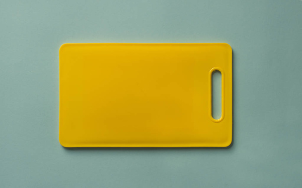Tagliere di plastica giallo colorato su sfondo blu, vista dall'alto
. - Foto, immagini