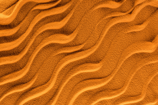 вид сверху на текстурированный песок с гладкими волнами и оранжевым цветовым фильтром
 - Фото, изображение