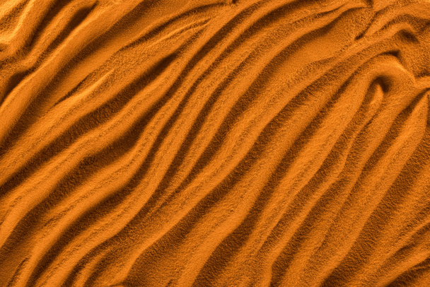 bovenaanzicht van textuur zand met golven en oranje kleur filter - Foto, afbeelding