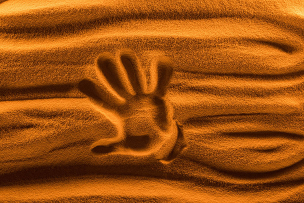 top view of hand mark on sand with color filter and smooth waves - Foto, imagen