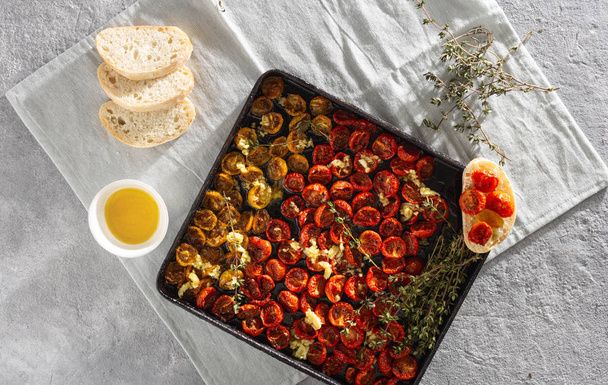 Red baked cherry tomatoes into baking tray on concrete background top view - Φωτογραφία, εικόνα