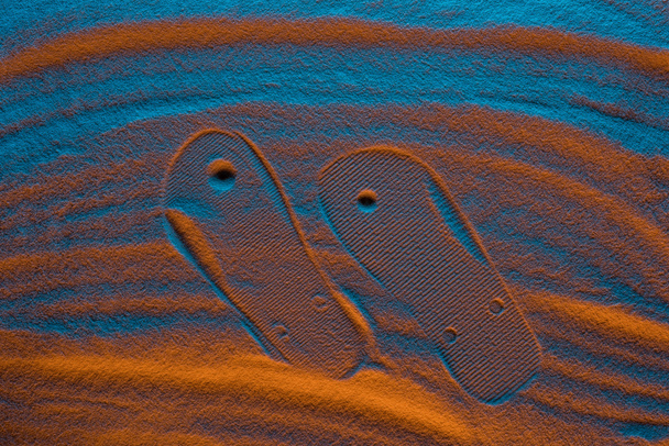 top view of flip flops mark on textured sand with color filter - Foto, immagini