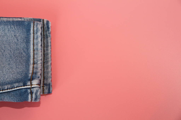 Folded blue jeans on a pink background. Postcard, there is a place for text. - Fotografie, Obrázek