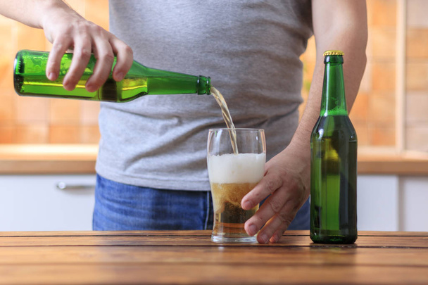 Miehet kaatavat olutta vihreästä pullosta lasiin
 - Valokuva, kuva
