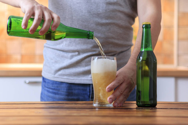 Miehet kaatavat olutta vihreästä pullosta lasiin
 - Valokuva, kuva