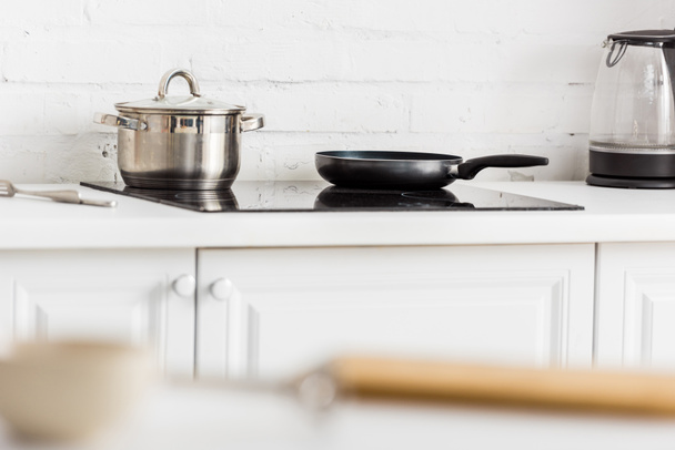 selective focus of stainless saucepan and black frying pan on electric stove in kitchen  - Foto, Imagem