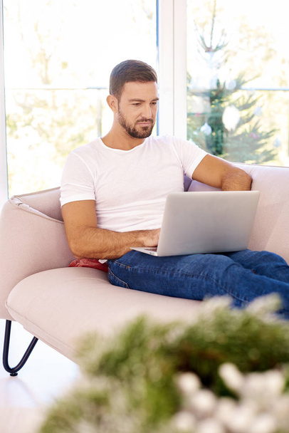 Портретний знімок красивого молодого чоловіка, який переглядає ноутбук під час сидіння
 - Фото, зображення