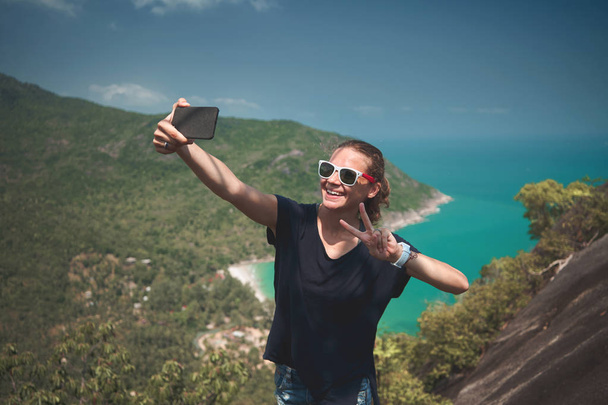 young woman traveler in sunglasses makes selfie with sea view - Фото, зображення