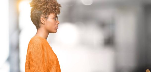 Krásné mladé afroamerické ženy nosí sluneční brýle izolované pozadí pohledu na stranu, uvolnit profilu pozice s přirozenou tvář s sebejistý úsměv. - Fotografie, Obrázek
