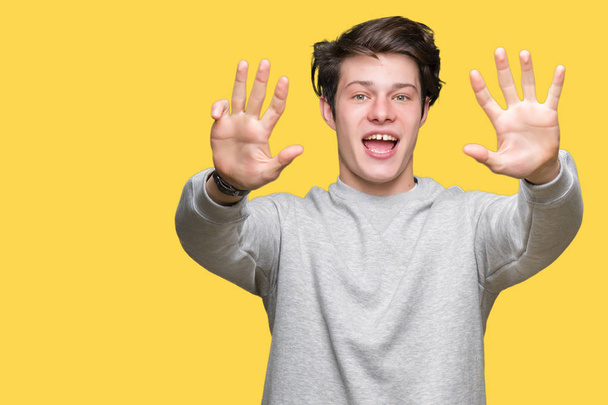 Young handsome sporty man wearing sweatshirt over isolated background showing and pointing up with fingers number nine while smiling confident and happy. - Photo, Image