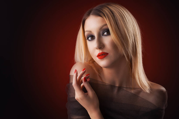 portrait of a blond woman. evening make-up on the red background - Photo, Image