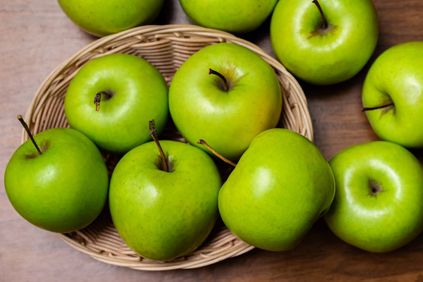 manzanas verdes en una canasta sobre una mesa de madera - Foto, imagen