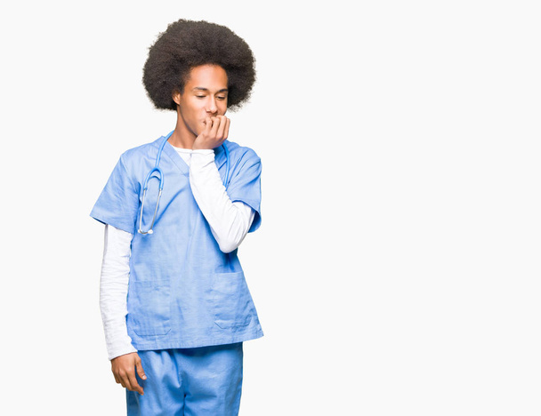 Nuori afrikkalainen lääkäri, jolla on afro-hiukset, näyttää stressaantuneelta ja hermostuneelta kädet suulla pureen kynsiä. Ahdistuneisuusongelma
. - Valokuva, kuva
