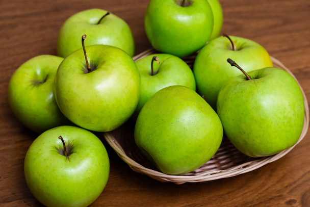 manzanas verdes en una canasta sobre una mesa de madera - Foto, imagen