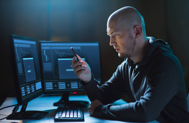 hacker with smartphone and computers in dark room - Фото, изображение