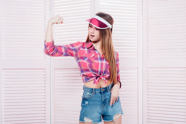 Sporty woman with pink hat posing on pink background - Foto, imagen