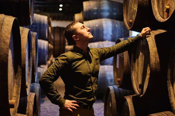 Професійний винороба чоловіки в старих традиційних дерев'яних бочок з вином в сховище вишикувалися в прохолодному і темному погребі в Італії, порту, Португалії, Франції - Фото, зображення