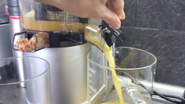 Frauenhand wechselt Krüge mit Apfelsaft. Saft fließt aus der Saftpresse. 4k-Video - Filmmaterial, Video