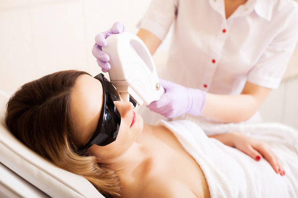 Cuidado com o corpo. Close-up de esteticista dando tratamento de compilação a laser para rosto de mulher jovem
 - Foto, Imagem