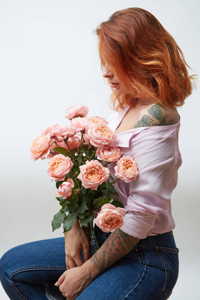 Sexy girl with a bouquet of delicate pink roses in a transparent vase on a gray background with copy space. St. Valentine's Day - Foto, imagen