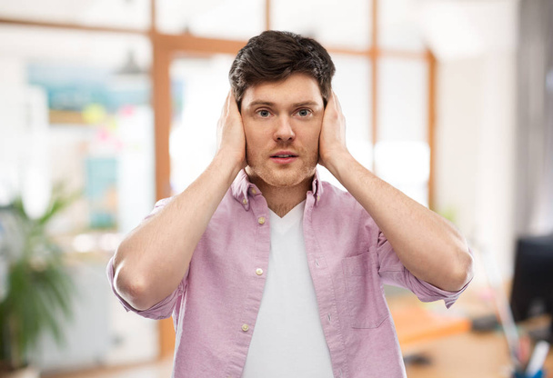 man closing ears by hands over office room - Photo, Image