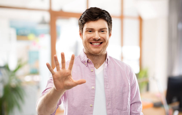 young man showing five fingers over office room - Foto, Imagem