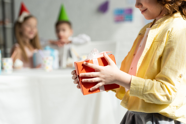 abgeschnittene Ansicht des Kindes mit Geschenkbox bei Geburtstagsfeier zu Hause - Foto, Bild