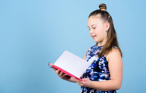 Fashion girl reading book. workbooks for writing. school diaries for making notes. small girl with pink note book. school child with exercise book. looking inside. schoolgirl holding lesson books - Foto, Imagen