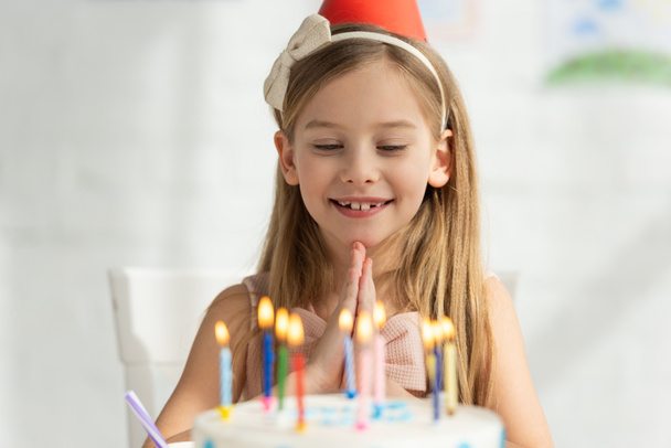 selective focus of adorable kid with birthday cake doing please gesture during party - Фото, изображение