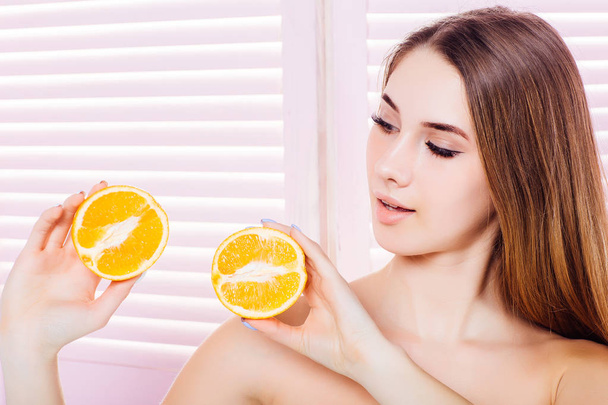 young woman with two halves of orange posing at camera  - Фото, зображення