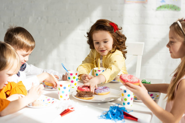 rozkošné děti sedícího na stranovém stole a oslavují narozeniny společně - Fotografie, Obrázek