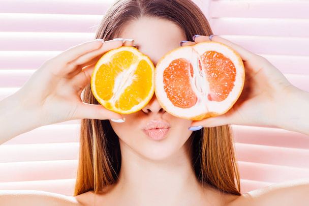 young woman with orange and grapefruit posing at camera - Zdjęcie, obraz