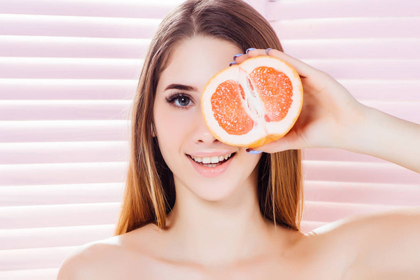 Gelukkige prachtige vrouw met schone huid en grapefruit poseren bij camera  - Foto, afbeelding